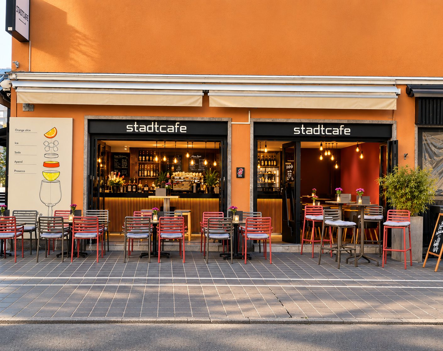 Die Fassade des Stadtcafés in der Maria-Theresien-Straße 49 mit zwei Eingängen, Markise und roten Stühlen auf dem Gehsteig